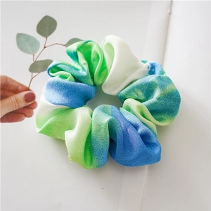 Detailed close-up of large tie-dye fabric scrunchie in refreshing green and blue tones