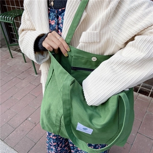 Detailed shot of green canvas tote bag with magnetic closure and interior zip pocket