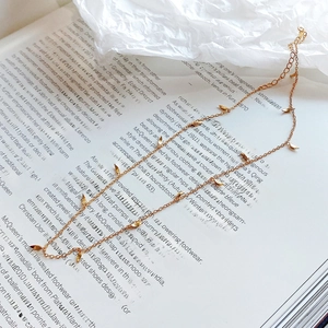 Detailed view of the gold leaf pendant necklace laid on a vintage fashion book