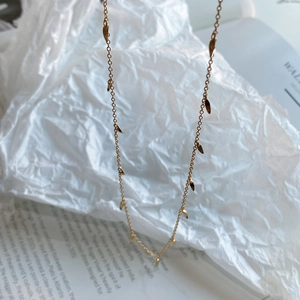 Detail of 925 sterling silver gold-plated necklace with elegant leaf pendants on paper