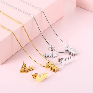 Gold and silver fishbone necklace and earrings jewelry set displayed on pink steps