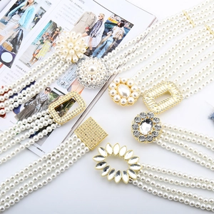 Detail view of multi-strand pearl elastic waist belts with various diamond buckle designs
