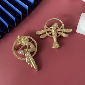 Close-up of vintage matte gold brooches with angel figures and white pearl details