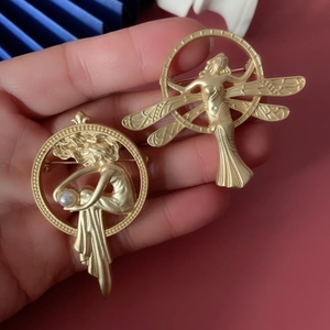 Macro detail of vintage matte gold baroque brooches with angel and pearl accents
