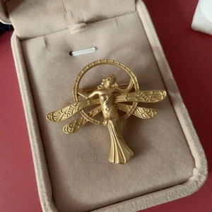 Detailed macro view of matte gold vintage angel brooch on velvet jewelry box