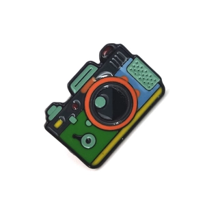 Detailed close-up of a colorful enamel camera brooch featuring mountain and forest scenery