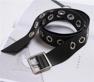 Detail of black PU leather belt with silver grommets and square buckle on a magazine
