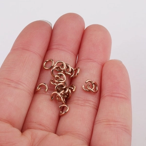 Close-up van 1x5mm roségouden roestvrijstalen open ringetjes op een vinger voor de schaal