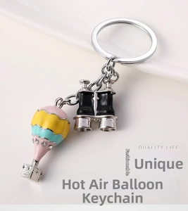 Detailed view of enamel hot air balloon and binoculars keychain with rhinestone accents
