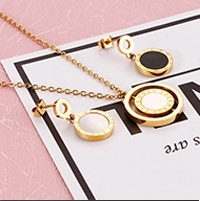 Close-up of gold-plated necklace and stud earrings set with black and white inlays