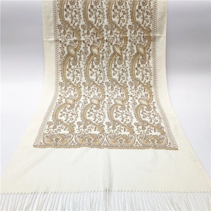 Detailed close-up of beige pashmina shawl with gold paisley embroidery and fringe trim