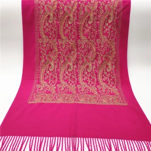 Close-up of rose red pashmina shawl featuring golden paisley embroidery and tassel trim