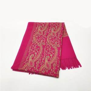 Macro view of rose red cashmere shawl featuring intricate golden paisley embroidery and tassels