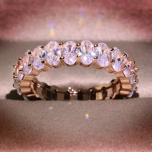 Luxury rose gold ring with sparkling oval-cut zircon stones on a silk background