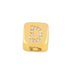 Macro shot of gold cube bead with micro-paved cubic zirconia forming letter D for jewelry