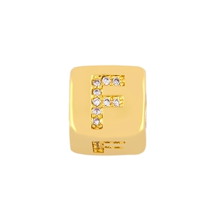 Macro shot of cubic gold plated bead with crystal encrusted letter F for DIY jewelry