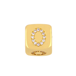Macro shot of gold cube charm featuring crystal micro-pave letter O on white background