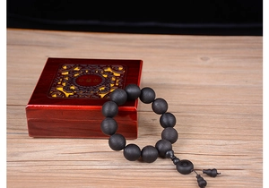 Détail de perles de prière en ébène dans un coffret de présentation laqué rouge