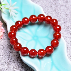 Polished 7A red agate crystal beaded bracelet displayed on a leaf shaped ceramic plate