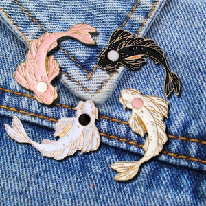 Detailed view of four koi fish enamel pins in pink black and white on blue denim jacket