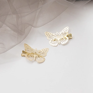 Détail de deux barrettes papillon dorées évidées sur un fond élégant de tulle gris