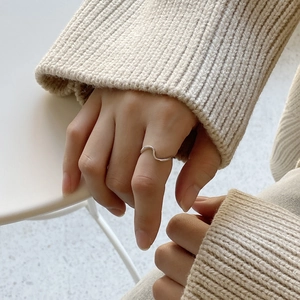 Detailed close-up of a wavy 925 sterling silver ring worn with a beige knitted sweater
