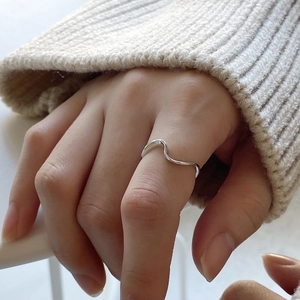Minimalist 925 sterling silver wavy Mobius ring shown on a finger with a warm vibe
