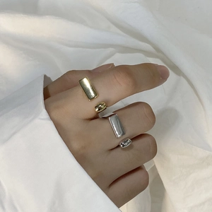Detail view of gold and silver geometric D-shape rings worn by a model in minimalist style