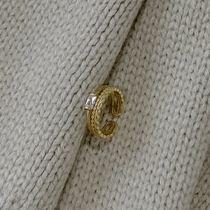 Macro detail of gold lace pattern sterling silver ring with rectangular white gem