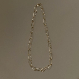 Detail of minimalist gold choker necklace featuring large irregular oval metal links