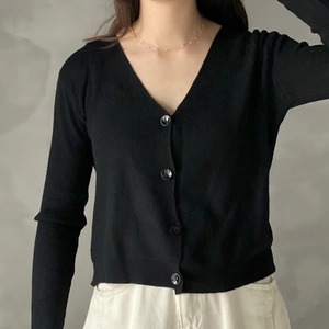 Close-up of minimalist black V-neck knit cardigan with textured fabric and matching buttons