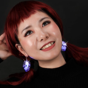 Close-up of glowing blue skull earrings on a model for Halloween parties