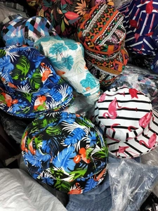 Close-up of assorted tropical print canvas bucket hats including flamingo and leaf patterns