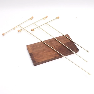 Golden T-bar jewelry stand with walnut wood base and metal hooks for necklace storage