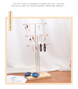 Detailed view of gold metal necklace stand with natural wooden base for jewelry display