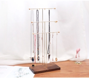 Three-tier gold metal necklace stand with walnut wood base and hanging hooks detail
