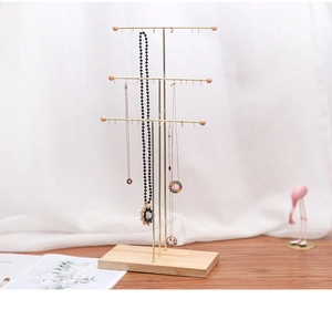 Detailed view of the three-tier gold metal jewelry rack with a solid wood base