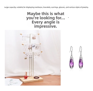 Detailed close-up of purple teardrop crystal earrings on a golden metal jewelry stand