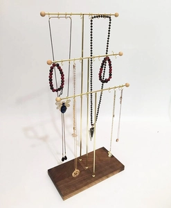Three-tier gold metal necklace stand with natural wooden base for jewelry display
