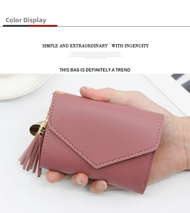 Close-up of dust pink short wallet featuring tassel pendant and heart-shaped metal charm