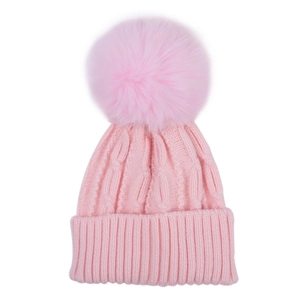 Detail of pink cable knit baby beanie featuring a large fluffy faux fur pom-pom topper