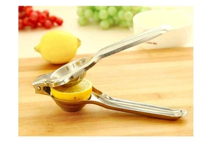 Close-up of manual stainless steel lemon squeezer pressing a fresh lemon half