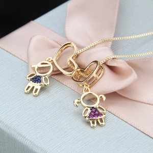 Close-up of gold heart and girl pendants with zircon stones on a gift box background