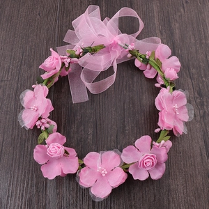 Bridal floral wreath headband with pink artificial roses and a large gauze bow on wood