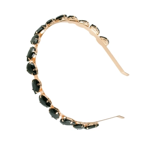 Detail of elegant gold metal headband with black oval gemstones on a white background