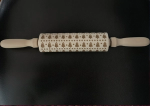 Detail of Christmas tree and stars embossed patterns on a wooden rolling pin surface
