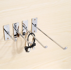 Close-up of wall-mounted stainless steel single hooks with hair accessories on wood wall