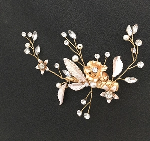 Détail d'une pince à cheveux de mariage avec perles, strass et fleurs dorées