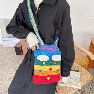 Rainbow crochet crossbody bag with cloud patch and pom-poms shown on a model
