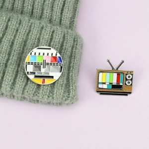 Detailed view of two retro TV signal test pattern enamel pins on purple background